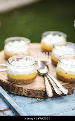 Close-up of individual servings of lemon meringue pies on a wooden chopping board with teaspoons Stock Photo