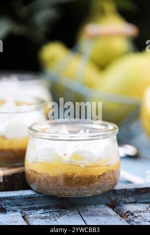 Close-up of individual servings of lemon meringue pies on a wooden chopping board with fresh lemons Stock Photo