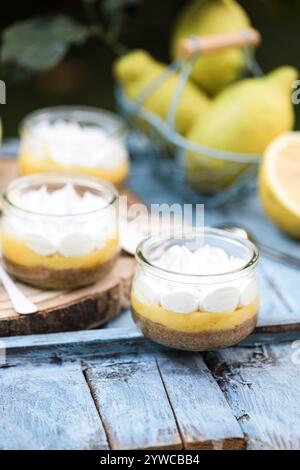 Close-up of individual servings of lemon meringue pies with fresh lemons on a wooden table Stock Photo