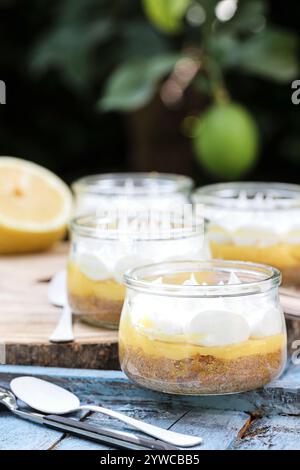 Close-up of individual servings of lemon meringue pies on a wooden chopping board with fresh lemons Stock Photo