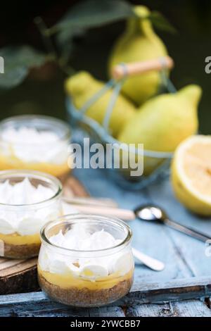 Close-up of individual servings of lemon meringue pies with fresh lemons on a wooden table Stock Photo