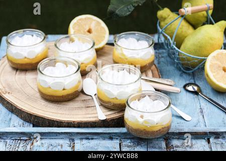 Close-up of individual servings of lemon meringue pies on a wooden chopping board with fresh lemons Stock Photo