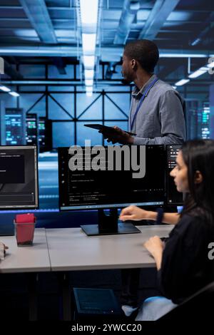 Engineer in data center updating systems to keeps performance up and protect servers from easily exploitable software vulnerabilities. Employee looking for errors causing servers to slow down Stock Photo