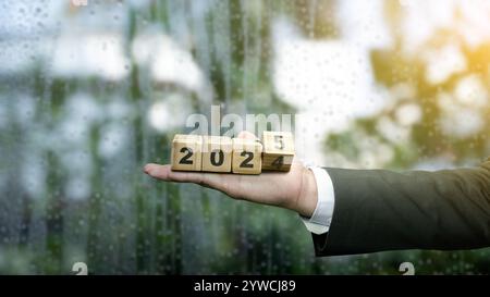 Business hand showing wooden cubes transform from the number 2024 to 2025. Happy New Year concept or Celebration Stock Photo