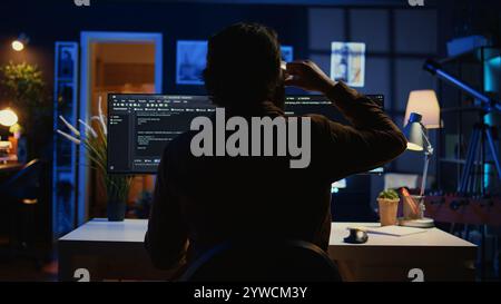 Software engineer writes complex binary code scripts on computer, close up. Teleworking IT specialist in home office using programming to safeguard consumer data, handheld camera shot, camera B Stock Photo
