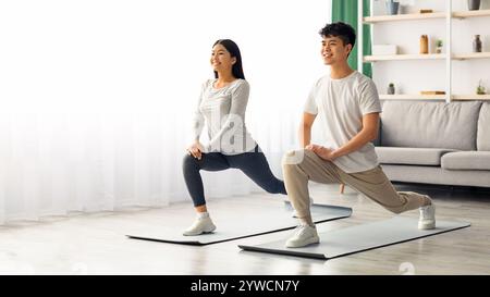 Motivated asian couple exercising at home, copy space Stock Photo