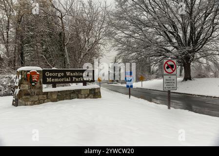 George Washington Memorial Parkway entrance during a winter snowfall, with snow-covered trees and road signs, creating a serene and picturesque scene. Stock Photo