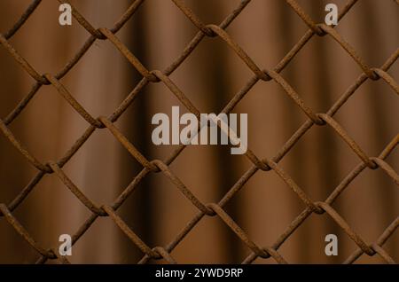 Rusty steel mesh fence background. Texture of rusty metal wire. Perspective metal mesh wall with blurred background. Stock Photo