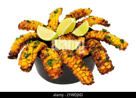 Portion of baked sweet corn ribs with herb garnish and lime wedges on a black bowl isolated on a white background Stock Photo