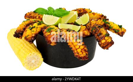 Portion of baked sweet corn ribs with herb garnish and lime wedges on a black bowl isolated on a white background Stock Photo