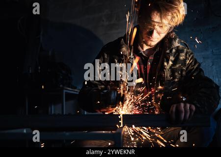 A man is working with metal using an angle grinder, with sparks flying around. Stock Photo