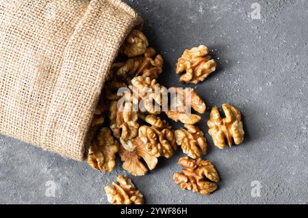Ripe and fresh walnut kernels in bowl or burlap sack without shell on rustic table, healthy nut food for brain Stock Photo