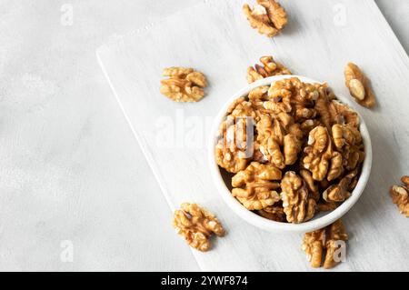 Ripe and fresh walnut kernels in bowl or burlap sack without shell on rustic table, healthy nut food for brain Stock Photo