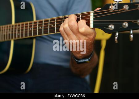 Close-up of a man's hands playing an E chord on acoustic guitar at home chord on acoustic guitar at home Stock Photo