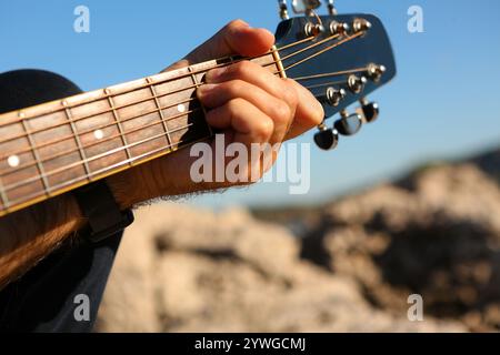 Close-up of a man playing the E chord on an acoustic guitar Stock Photo