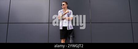 Handsome young man with a prosthetic leg leans against a stylish wall, exuding confidence. Stock Photo
