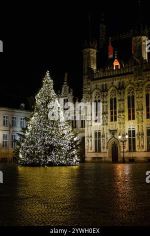 View of a giant Christmas tree decoration and an illuminated town hall on 'de Burg' square in Bruges in West Flanders, Belgium. Stock Photo