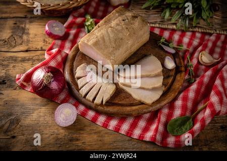 Smoked lard with spices, onions and herbs lying on wooden cutting board Stock Photo