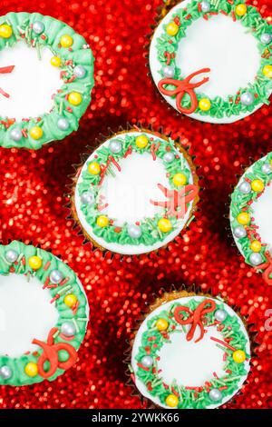 close up detail of christmas mincemeat cakes  mince pies covered with white gold green and red icing on a festive red glitter and holiday background Stock Photo