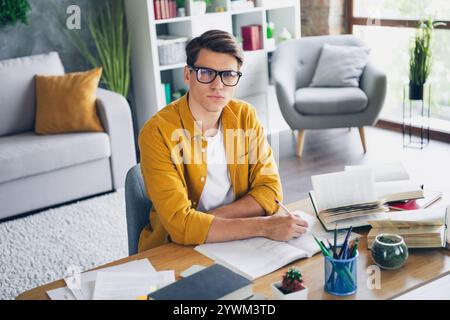 Young man in casual wear studying at home in bright, stylish apartment interior Stock Photo
