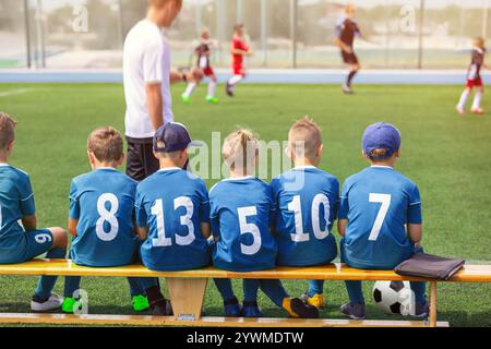 Kids in the Football Team. Young Football Players. Young Soccer Team Sitting on Wooden Bench. Soccer Match For Children. Young Boys Playing Tournament Stock Photo