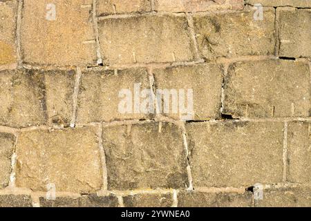 Textured stone wall displays various weathering patterns formed over time, highlighting the craftsmanship involved in constructing this historical str Stock Photo
