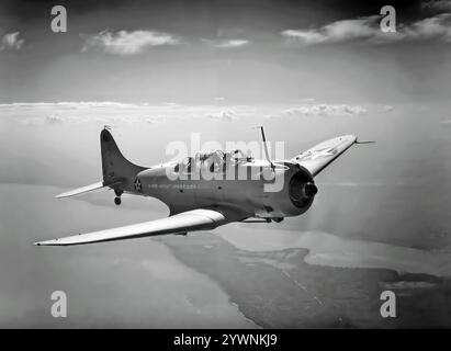 A Douglas SBD Dauntless World War II American naval scout plane and dive bomber in flight. From 1940 to 1944, the aircraft was the United States Navy's main carrier-based scout/dive bomber and also flown by the United States Marine Corps, both from land air bases and aircraft carriers. An effective naval scout plane and dive bomber with long range, good handling characteristics, maneuverability, potent bomb load and great diving characteristics, it's best remembered as the bomber that delivered the fatal blows to the Japanese carriers at the Battle of Midway in June 1942. Stock Photo