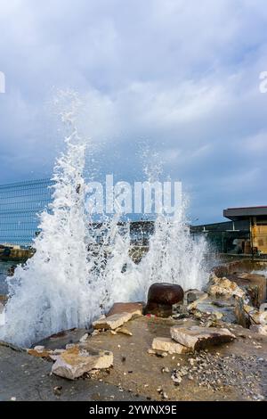 Crashing Waves on a Weathered Pier. The raw energy of the sea, with water erupting into dramatic splashes against a seaside construction Stock Photo