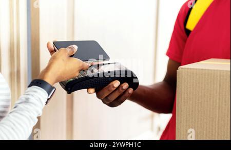 Unrecognizable Black Woman Paying For Delivered Parcel Using Smartphone Indoor Stock Photo