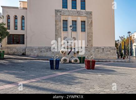 A large teddy bear dressed in Christmas ribbons and large gift wrapped boxes on the street in the island of Kos, Greece. Stock Photo