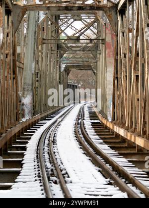 snow-covered railway tracks on an Old metal Bridge in Winter. steel frame railway bridge. closed train bridge Stock Photo