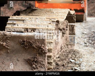 Close-Up View of Muddy Excavator Tracks on Construction Site. Excavator sprocket with mud. iron caterpillars of the bulldozer of the tractor on the ro Stock Photo