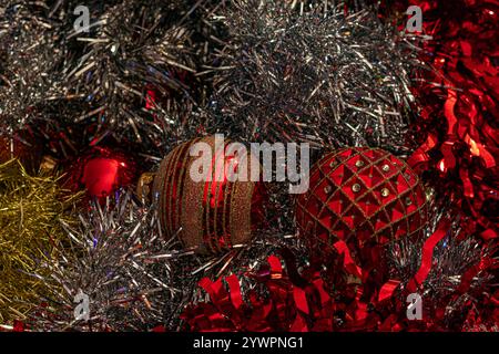 array of red and gold Christmas ornaments, each uniquely designed, surrounded by shimmering silver tinsel, creating a festive holiday scene Stock Photo