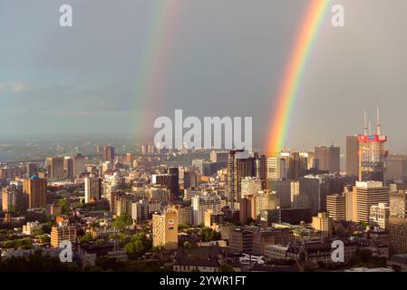 A vibrant double rainbow illuminates the skyline of Montreal, Quebec, Canada, with the city's urban architecture and iconic landmarks under a dramatic. Stock Photo