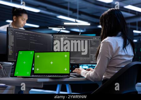 Coworkers in data center using green screen laptop and tablet to find firewall misconfigurations affecting servers. Colleagues in server room checking systems bottlenecks using mockup devices Stock Photo