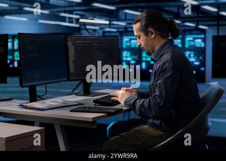 Admin typing on computer keyboard, doing maintenance in data center to extend equipment life span and avoid downtime. IT specialist monitoring blade servers for overheating problems Stock Photo