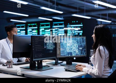 Team of specialists working on PC in data center with artificial intelligence tech to process massive datasets. Engineering colleagues solving tasks in server hub storing data used for deep learning Stock Photo