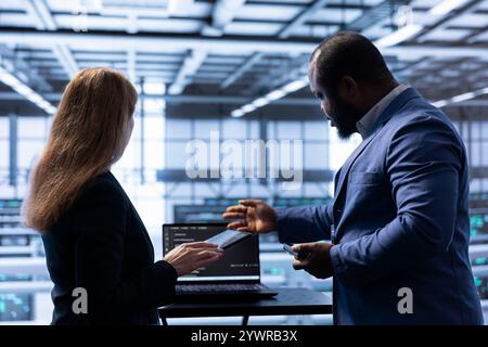 Admin and manager doing disaster recovery planning and security protocol enforcement in data center. Coworkers doing brainstorming in server room to reduce downtime, ensuring business continuity Stock Photo