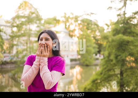 Peruvian student enjoying a day at el retiro park in madrid, covering her mouth while laughing Stock Photo