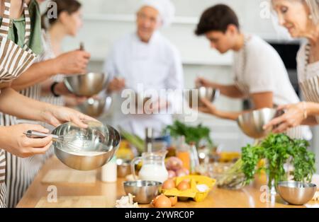 People mixing sauce in bowl with whisk at culinary class Stock Photo