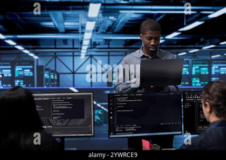 Admin doing routine maintenance in data center to extend equipment life span and avoid downtime. Worker monitoring servers for issues such as overheating or power fluctuations Stock Photo