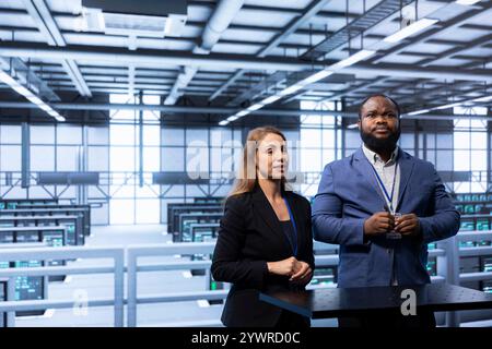 Admins in data center tracking network traffic and activity using augmented reality technology and installing software updates. Coworkers performing database backups using AR tech visualization Stock Photo