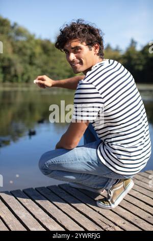 young happy man feeding ducks in the pond Stock Photo