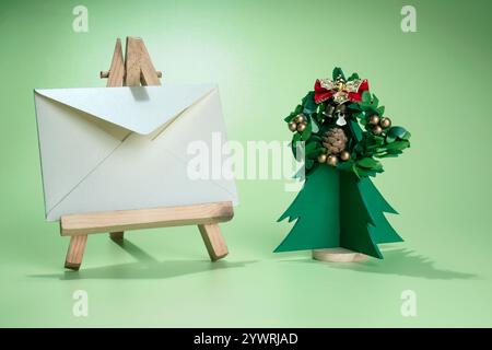 Closeup view of a Christmas tree miniature and Christmas wreath with an envelope on a wooden easel with a colored background. Mockup, blank template, Stock Photo