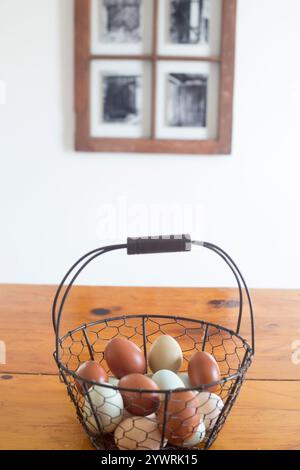 A basket of eggs sits on a farm table in a kitchen, Stock Photo