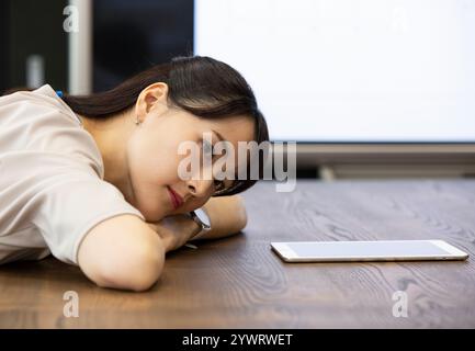 Japanese business woman lying face down on table Stock Photo