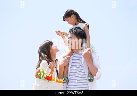 Mother and child holding hands with father carrying child on shoulder Stock Photo