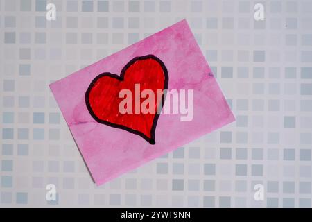 A red love heart drawn on a sticky note or post-it stuck on a wall Stock Photo