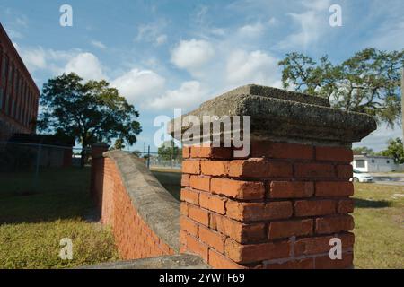 Leading line down edge broken Old red brick masonry wall with bright blue sky. Rectangle pattern of bricks with street in back. Stock Photo