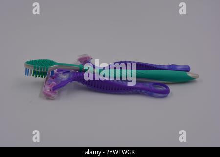 Women's things, things are made of plastic. Two women's purple machines for being armpits, a green women's toothbrush are arranged on a black plastic. Stock Photo